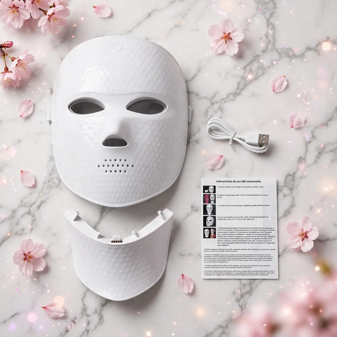 Mascarilla LED blanca sobre mármol con flores rosadas
